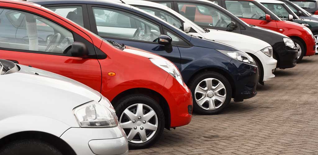Silver, red, blue, and black cars lined up in a lot