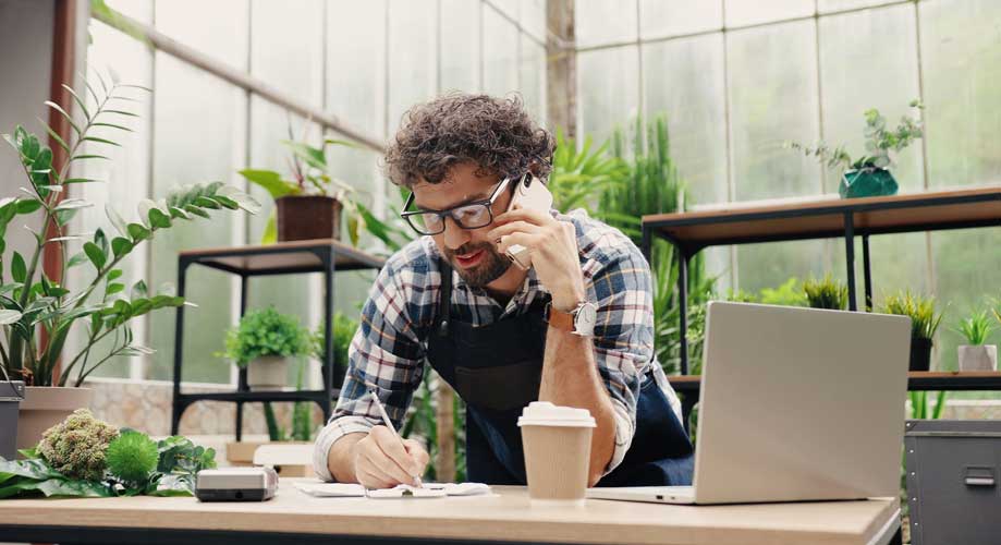 Joyful male florist calling on smartphone at work