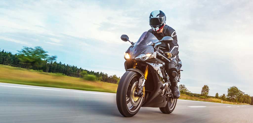 Man Riding Motorcycle On Road Against Cloudy Sky