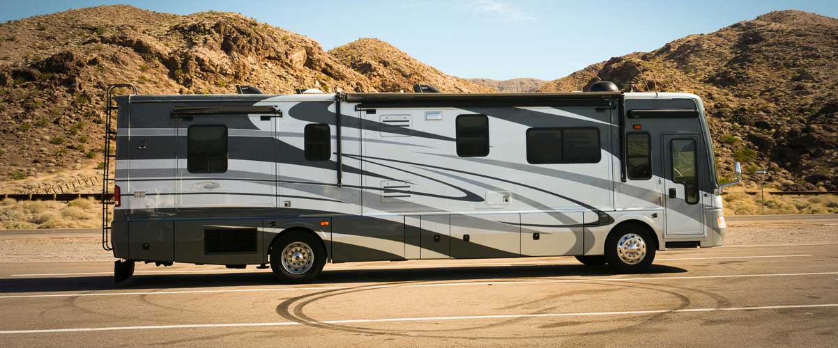 A white and gray RV on a road in a desert