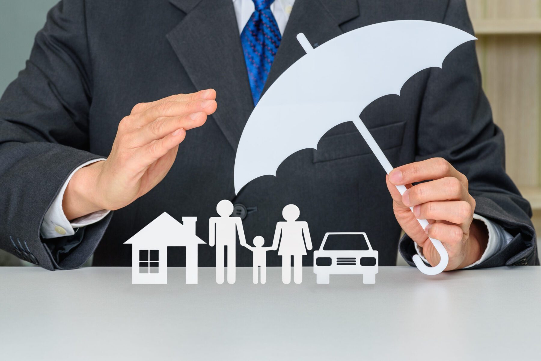 Man in a suit holds an umbrella to protect family