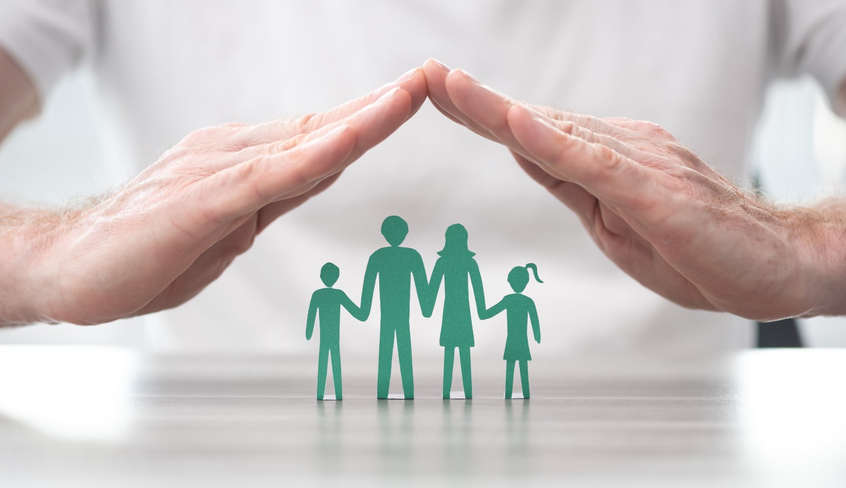Hands covering a small silhouette of a family