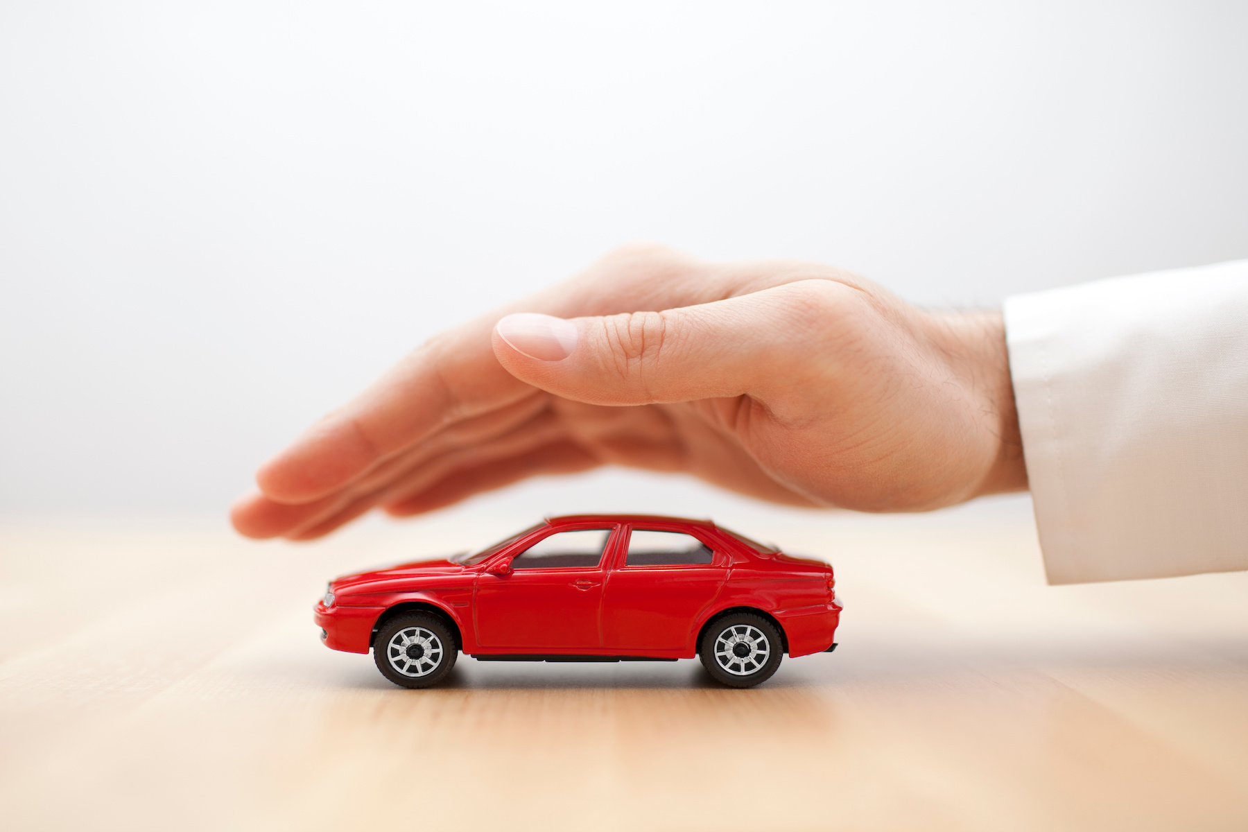 Hand over car toy signifying car insurance
