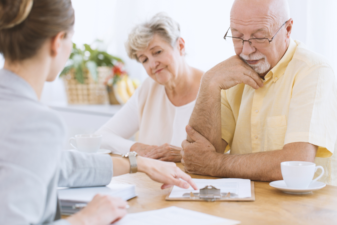 An older couple meet with an insurance agent to discuss types of life insurance.