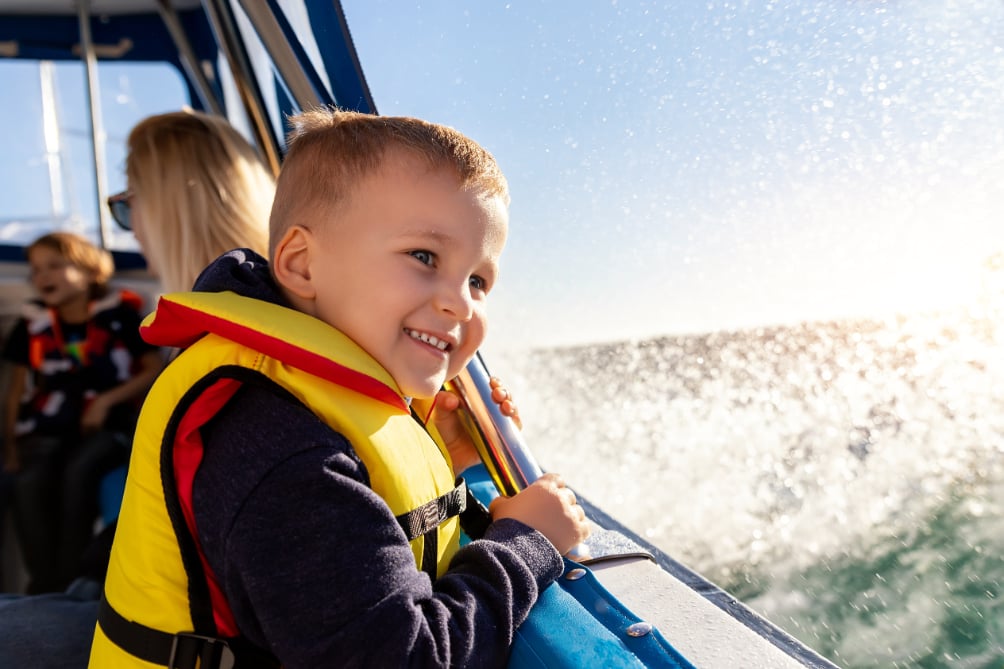 Blond young boy with life jacket on boat