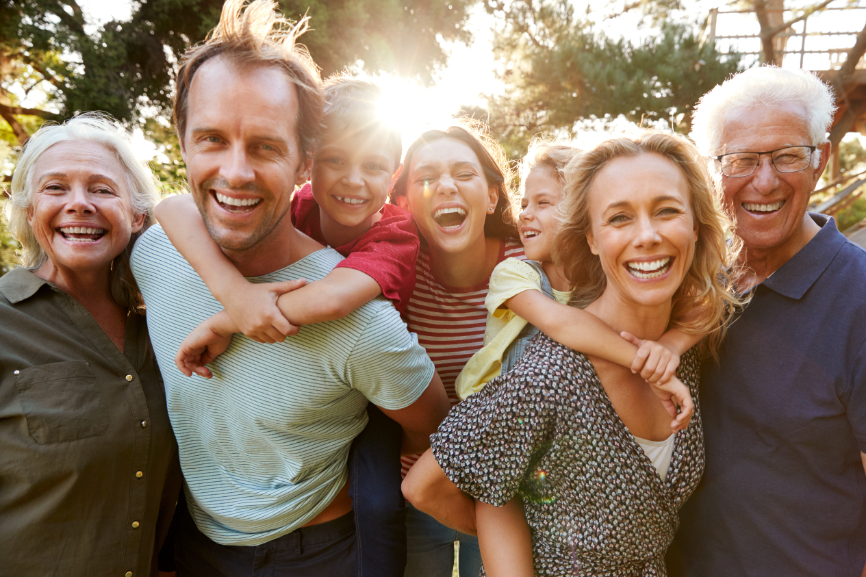 Family hugging and smiling with sunset on the back