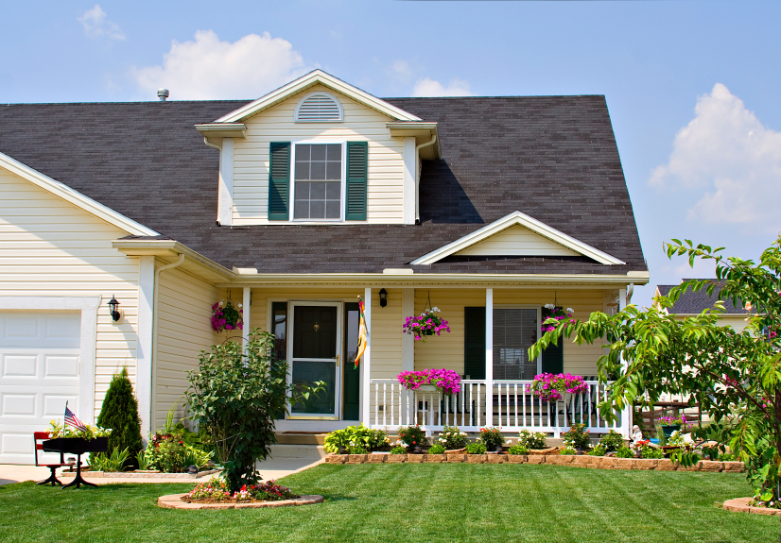 Beautiful white house with pink flowers in front and a small tree