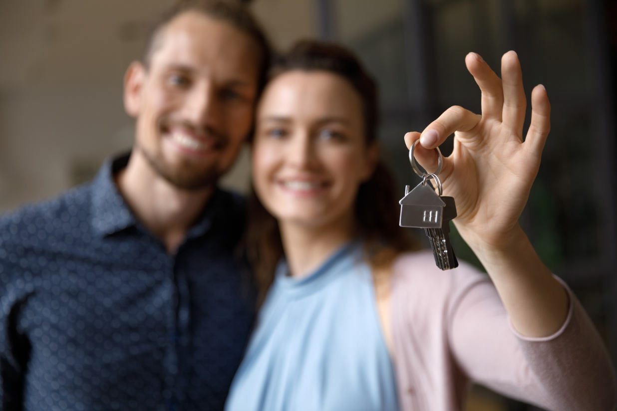 Couple smiling and holding keys with house keychain.