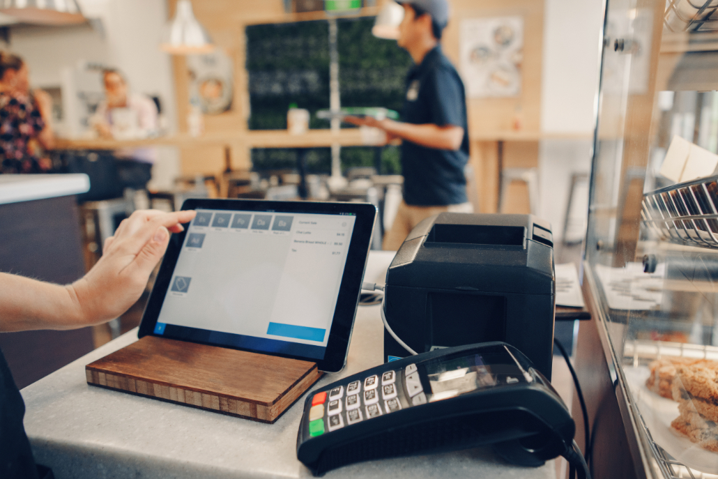 Cashier utilizing tablet next to payment terminal in a small restaurant