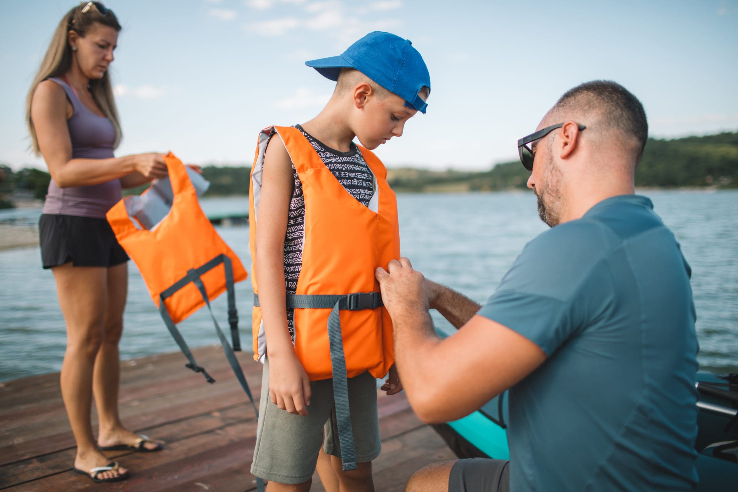 Father helping his son put on a life jacket.