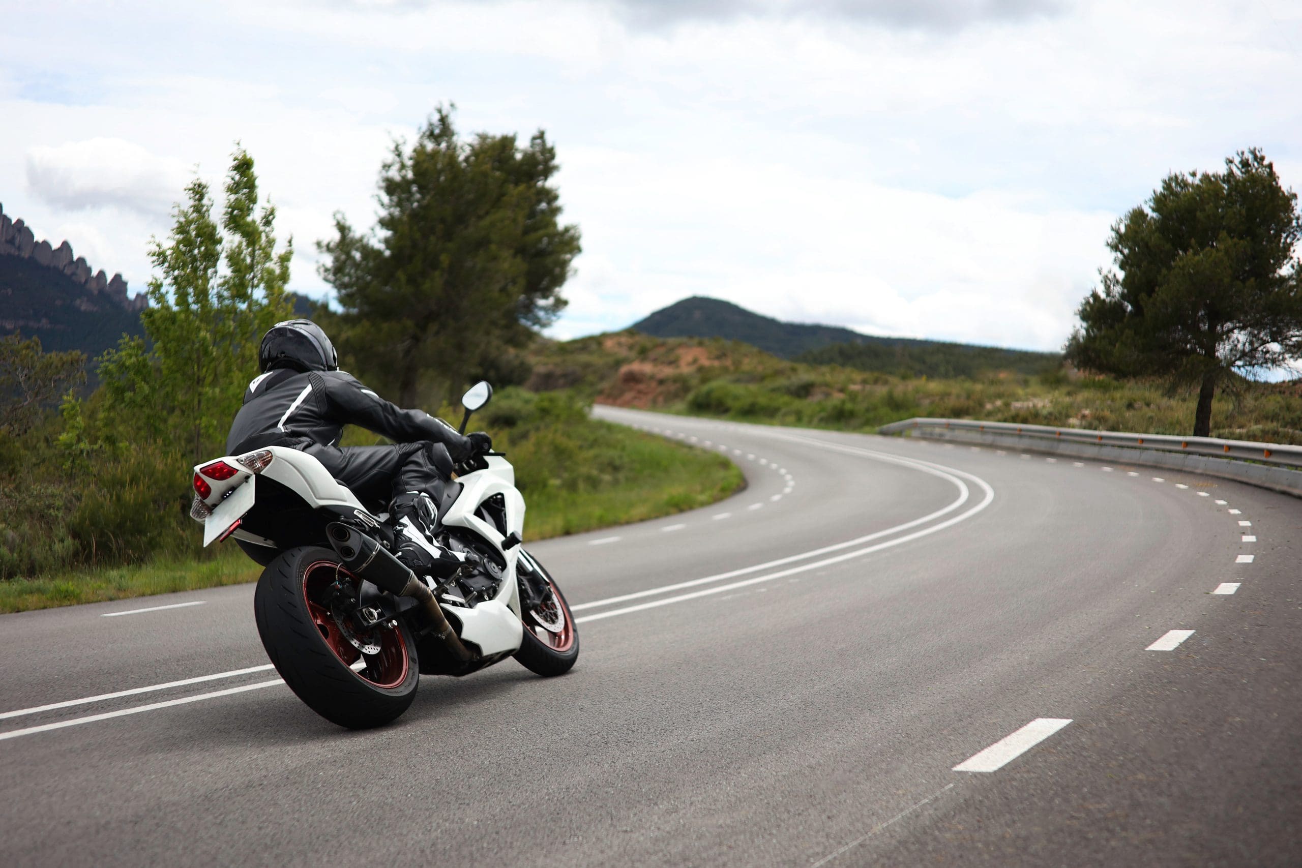 Biker in a black uniform driving a white sports motorcycle