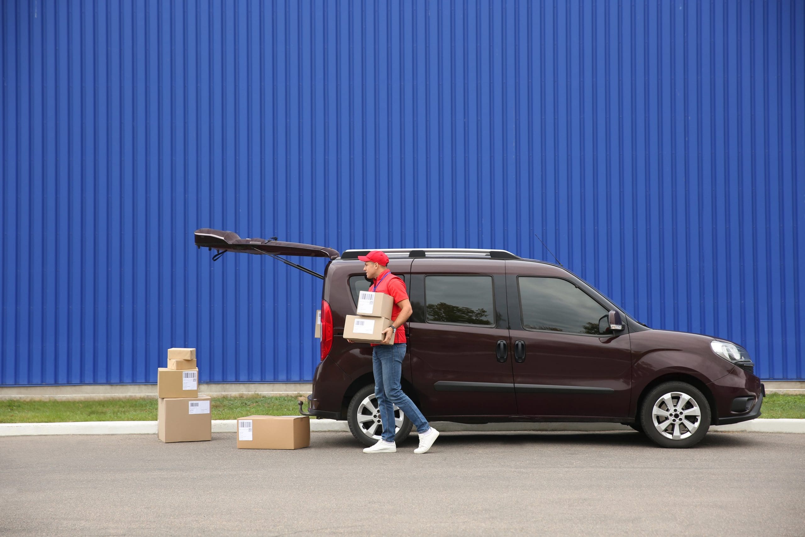 Courier loading packages in car outdoors.