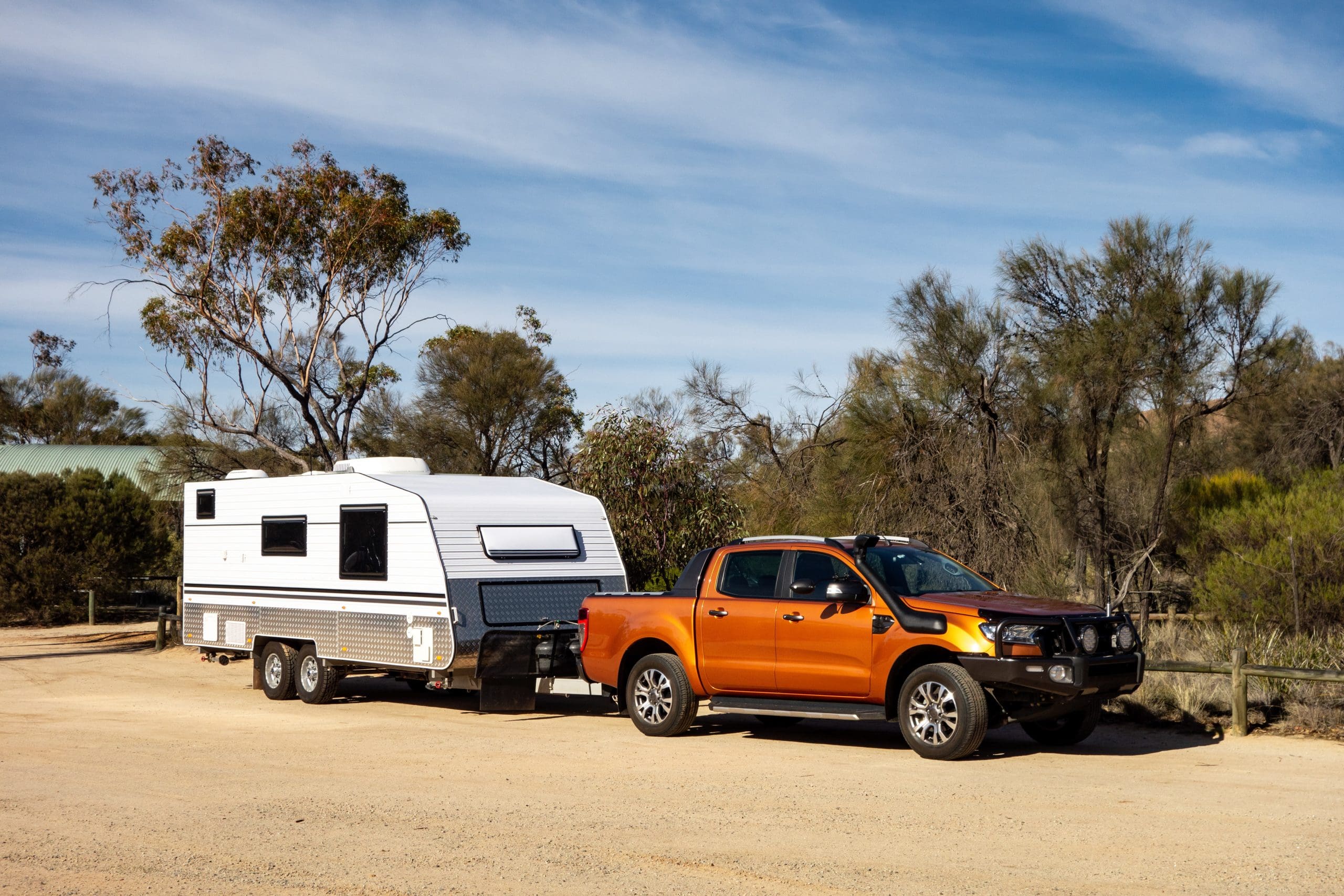 Off road pickup car with air intakes and a white caravan trailer .