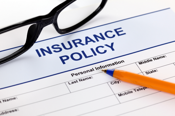 Close up of insurance policy, pecil and glasses.